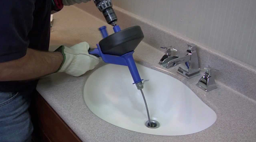 Technician feeding a drain snake cable into a residential drain
